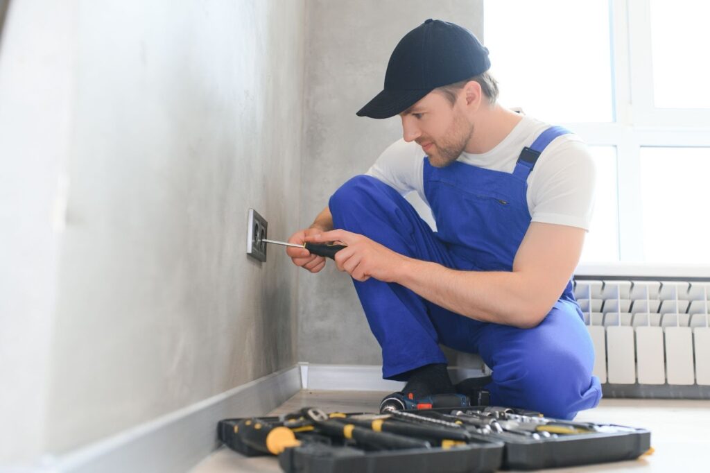 Electrician installing a new outlet inside a modern apartment.
