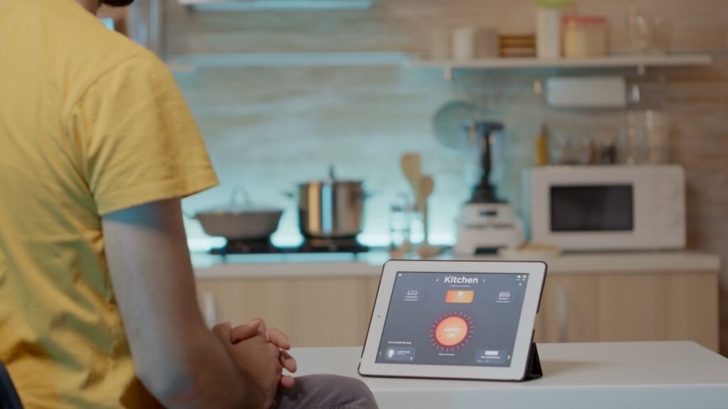 Man checking smart system settings on a tablet resting on the kitchen table.