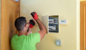 A licensed electrician installing a residential circuit breaker panel inside a home.
