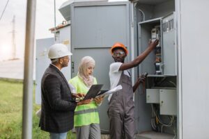 A team of commercial electricians work on a large junction box.