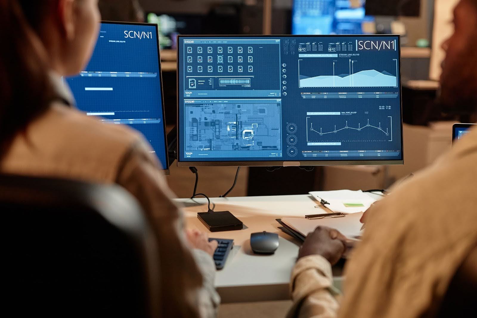 Two developers look at data charts using a SCADA system.
